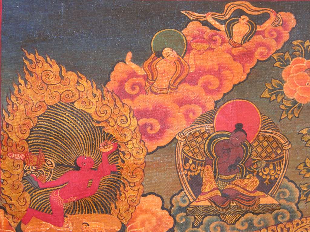 Chakrasamvara Mandala 03 Upper Left - Vajrayogini Outside the mandala at the four corners are four depictions of Vajrayogini (Tib. Naro Khacho), the dakini of wisdom. Her right hand brandishes a curved flaying knife topped by a vajra, and in the left she holds a skull-cup filled with the swirling brains and entails of the enemies of the Dharma. The curved knife was the instrument used to annihilate these enemies. Her left shoulder supports a staff known as the khatvanga, representing her consort Chakrasamvara. This indicates that he and Vajrayogini are inseparable, whether he is explicitly presented together with her or not.